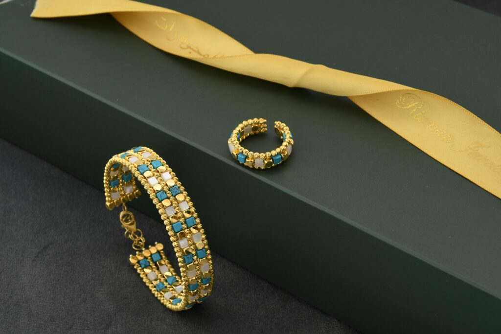 Luxurious gold and turquoise bracelet and ring set displayed elegantly on a green gift box with a golden ribbon.